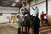Volunteers and riders gathered around a therapy horse during a lesson