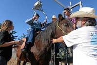 A therapy horse and rider walking together outside the arena